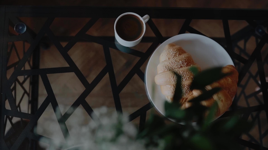 Woman is puttin on the table coffee cup. Fresh Сroissants. Good morning and wake up. Cozy moody, weekend  and relax at home. Tasty sweet breakfast. 