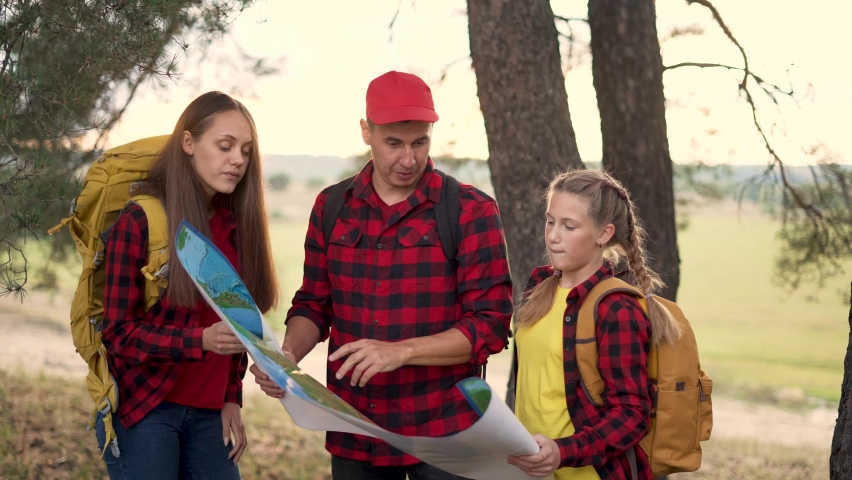 Family tourism with map in forest. Team orienteering in forest. Family travel with map. Teamwork concept. Team of tourists in a forest park with a map. Tourists hiking. Family travel in forest park Royalty-Free Stock Footage #1084944577