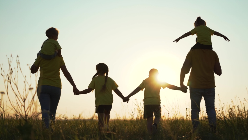 Happy family concept. Dad mom and children walk at sunset in the park. Active lifestyle concept. Parents with children holding hands at sunset. Happy family having fun in park. Silhouette of family Royalty-Free Stock Footage #1084944610