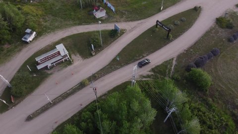 Aerial top view of a black car driving from rural road to main route in natural background at Mar de las Pampas, Argentina