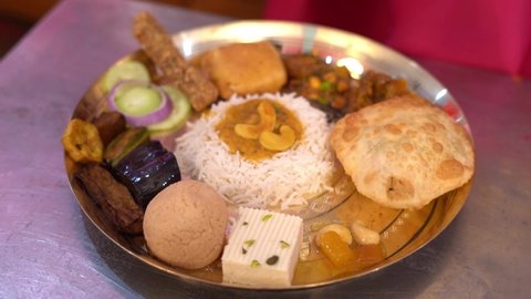 Close up shot of dish beautifully decorated over the silver plate. A Bengali meal with rice vegetable and different type of dessert in a large plate at the occasion of baby rice ceremony