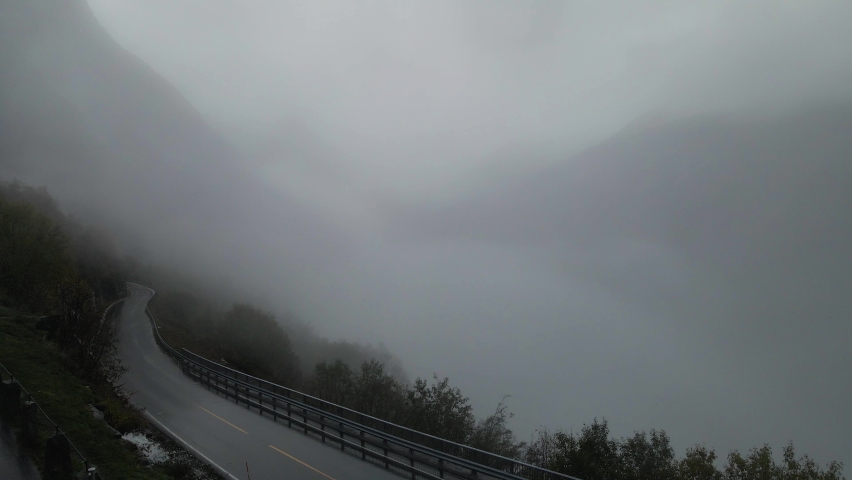 Empty Mountain Road Shrouded With Clouds and Fog Near Geirangerfjord In Norway. - aerial