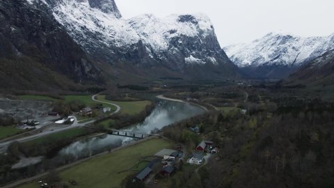 Bridge Over Rauma River In Andalsnes, Norway With Snowy Trollveggen Mountain Massif In Background. wide aerial