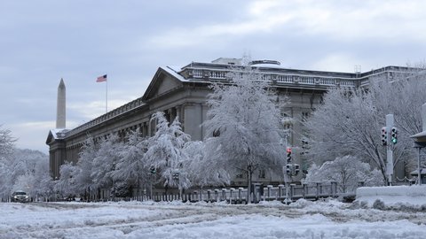 Washington, DC - USA - January 3 2022: The U.S. Treasury Building seen covered in snow after a winter storm. The Washington Monument is seen in the background.