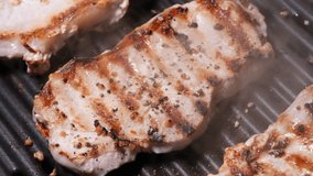 Close up view on Meat with golden crust is fried on an electric grill close up. 4K resolution video. Pork steaks close up are fried and smoked on the grill.