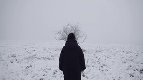 Moody shot of a woman approaching a lonely tree in a frozen winter fog. - Powered by Shutterstock - Get 15% off with code: PIKWIZARD15