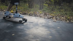 A young man with a metal prosthetic leg rides a skateboard in an autumn park. Go in for sports with an artificial leg. a11y - Powered by Shutterstock - Get 15% off with code: PIKWIZARD15
