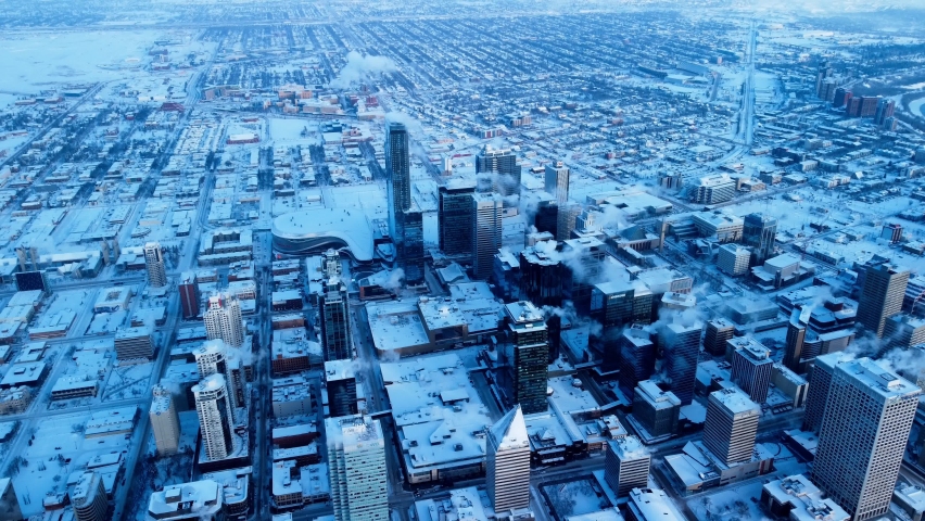Edmonton city downtown winter aerial snow cover high rise building reflective mirrored glass financial residential commercial stadium towers reverse flight backwards at a mass altitude overlooking all