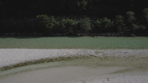 Video of a drone with a side plane "slide" over the crystal clear turquoise water of Lake Isonzo.
left to right