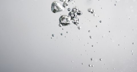 Close Up Lockdown Shot Of Bubbles Moving And Rising In Water Against White Background