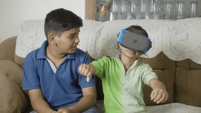 Girl kid using VR or virtual reality goggles in front of his brother - concept of technology addiction and childhood entertainment.