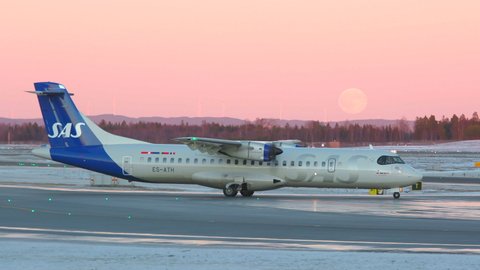 Oslo Airport Norway - December 16 2021: propeller airplane sas taxiing evening very peri pantone colors full moon horizon side view
