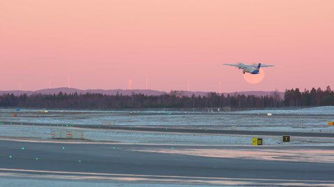 Oslo Airport Norway - December 16 2021: propeller airplane sas taking off evening very peri pantone colors passing full moon horizon