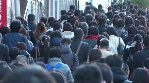 TOKYO, JAPAN : Crowd of people walking down the street in busy morning rush hour. Many commuters going to work in winter season. Japanese business, job and lifestyle concept. Slow motion, back shot.