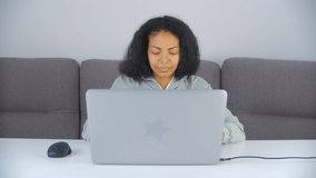 Focused freelancer woman working at home. Black female doing distant work online on laptop computer. 4k stock video of freelance writer person typing text on notebook keyboard in living room