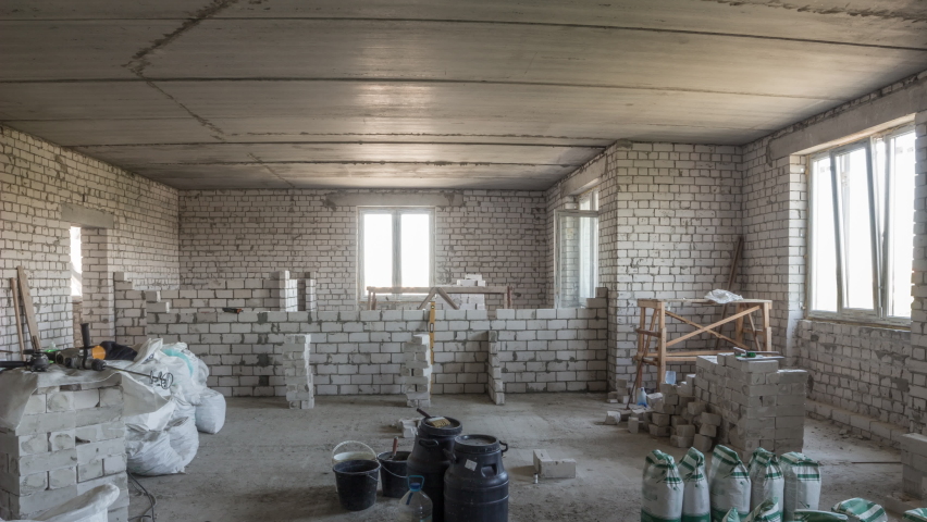 Builders laying brick walls inside appartment with professional tools timelapse. Workmen at work, bricklayers building wall, contractor and worker. Building materials around