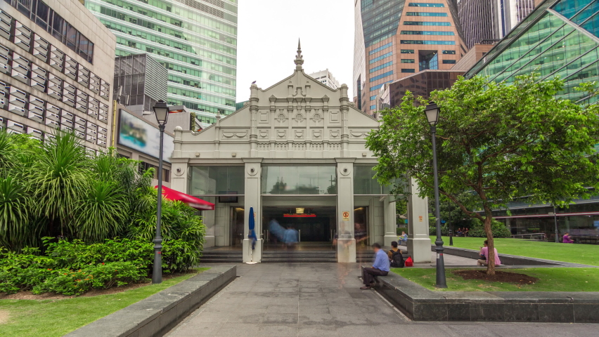 Exit from metro station snd skyscrapers at Raffles Place in Singapore Financial Centre timelapse hyperlapse. Green lawn. People walking around Royalty-Free Stock Footage #1084969081