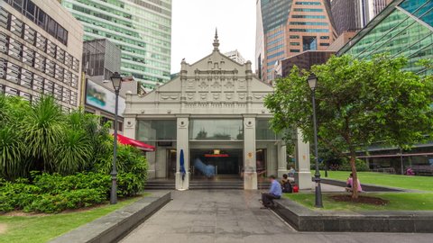 Exit from metro station snd skyscrapers at Raffles Place in Singapore Financial Centre timelapse hyperlapse. Green lawn. People walking around