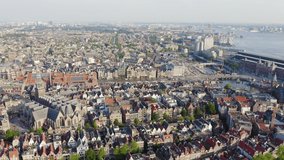 Inscription on video. Amsterdam, Netherlands. Flying over the city rooftops towards Amsterdam Central Station ( Amsterdam Centraal ) and around the Oudekerk church ( De Oude Kerk ). Arises from blue
