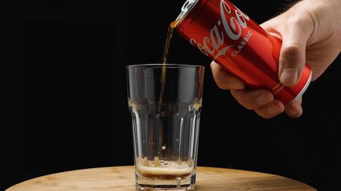 A man's hand pours a Coca-Cola from a can into a glass. The camera flies around. Parallax effect. Close-up. Russia, Krasnodar, December 24, 2021
