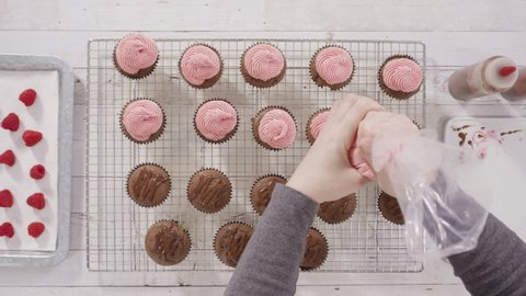 Time lapse. Flat lay. Frosting chocolate cupcakes with raspberry cream cheese buttercream.