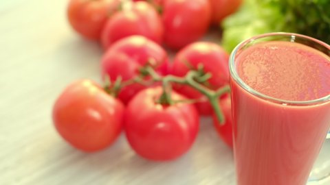 tomato juice with sprig of tomatoes on background. Tomato juice is poured into a glass.