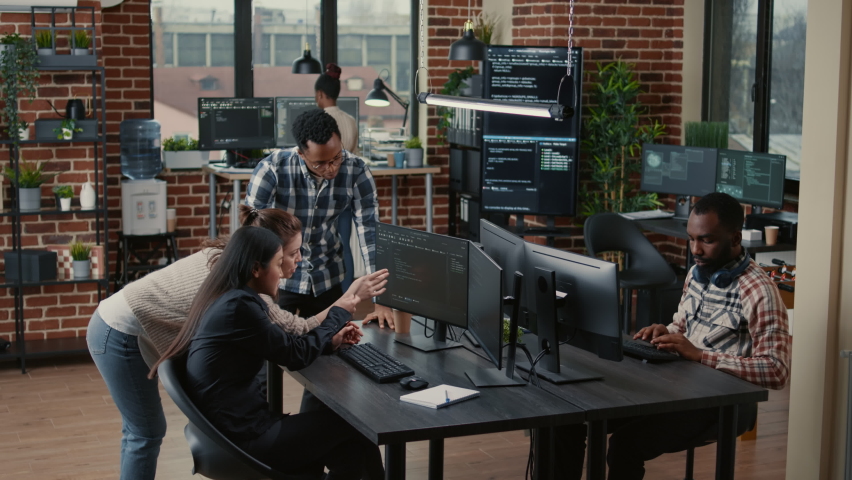 Junior dev programmers collaborating on group project compiling algorithm asking senior developer for help while intern joins the discussion. Software engineers brainstorming ideas looking at screens. Royalty-Free Stock Footage #1084977337
