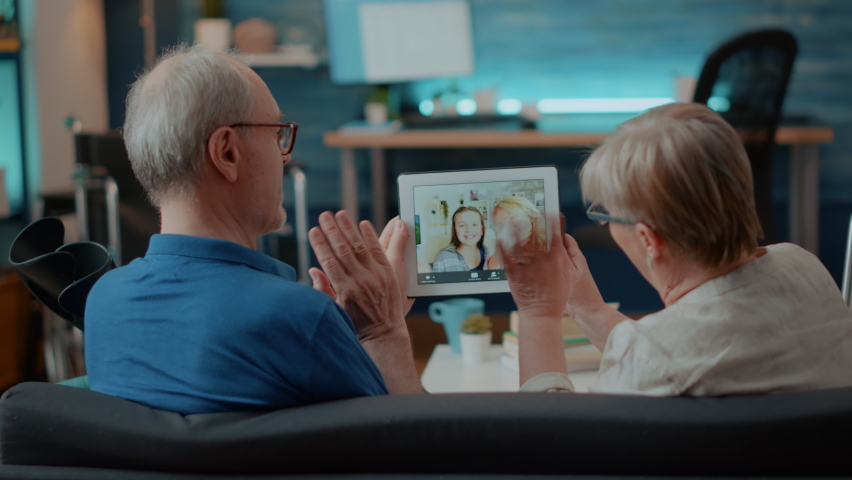 Grandparents talking to family on online conference chat in living room. Senior couple using digital tablet to talk to niece and daughter on remote video teleconference for communication. Royalty-Free Stock Footage #1084977493