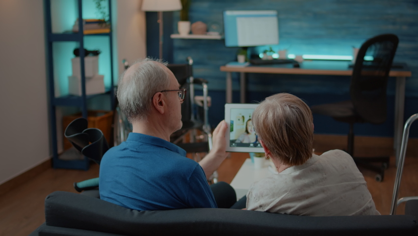 Old couple attenting video call meeting with woman and little girl on tablet. Cheerful grandparents chatting with family on remote teleconference, using online communication on gadget. Royalty-Free Stock Footage #1084977535