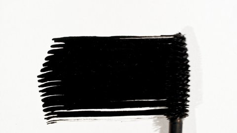 Macro shot and slow motion of a black mascara isolated on white background. Professional makeup. Closeup of a mascara wand on white background.
