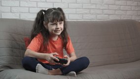 Child play video game on playstation. A view of happy little girl play video game on her playstation in the room.