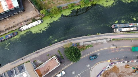 Cars and cyclists ride by Regents Canal and canal house boats in Bethnal Green, East London, England. Ariel view.