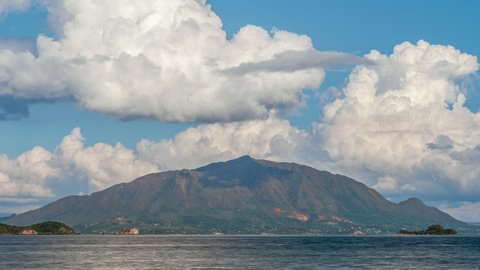 The famous mountain peak, Mont Dore in New Caledonia as seen from across the bay with huge cumulus clouds forming and dissipating above the island - time lapse