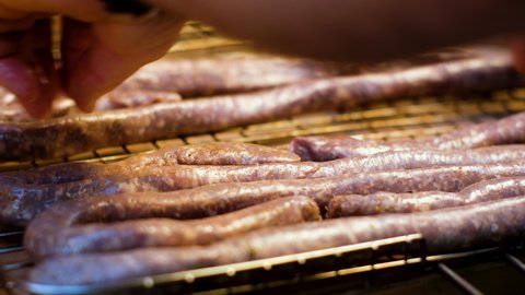 Placing traditional farmer's sausage on the grid, ready to barbecue