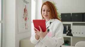 Young redhead woman wearing doctor uniform using touchpad at clinic - Powered by Shutterstock - Get 15% off with code: PIKWIZARD15