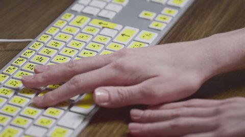 Close-up of a computer keyboard with braille. A blind girl is typing words on the buttons with her hands. Technological device for visually impaired people. Tactilely touches bumps on the keys