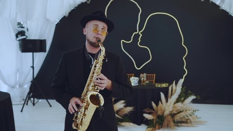 Nizhny Novgorod, August 15, 2021. The saxophonist plays and dances against the background of the presidium of the newlyweds