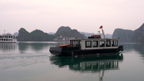 CRUISE BOATS AND TENDER VEHICLE IN HA LONG BAY, CAT BA NATIONAL PARK, NORTH EAST VIETNAM – 4 APRIL 2018 The limestone islands in UNESCO World Heritage site, HaLong Bay, Cat Ba National Park, Vietnam