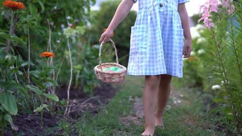 little girl looking for Easter eggs with basket in hand, entertainment for children in Catholic Easter, close-up of legs
