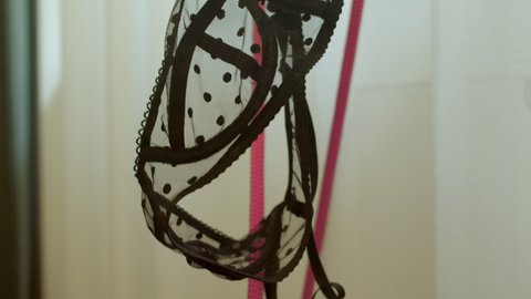 The bra is hanging on a red hanger. The woman leaves the laundry before resting the body. Decoration with dots. Wardrobe item. Camera movement.