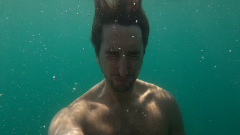 Man under water holding breath submerged
