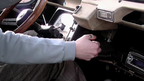 Young Man Turning the Ignition Key of a Vintage Car. Close Up.