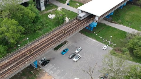 Subway train coming out of station over a bike path and parking lot