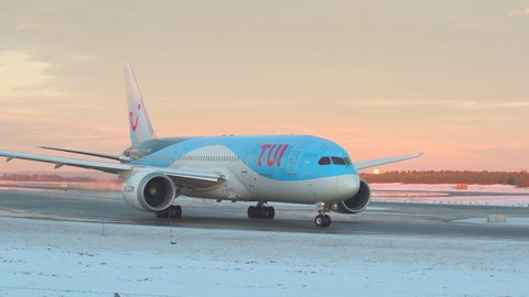Oslo Airport Norway - December 17 2021: tui airways airplane boeing 787 taxiing beautiful winter pantone colors in sky
