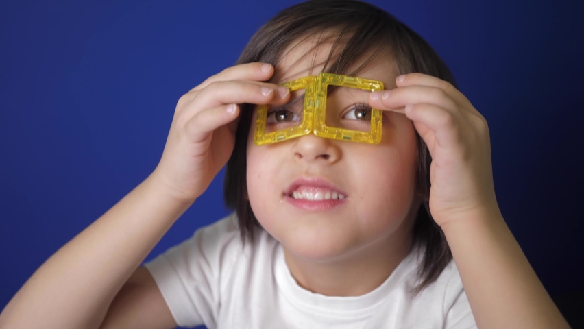 funny boy child made yellow glasses out of a magnetic constructor and put them on his eyes