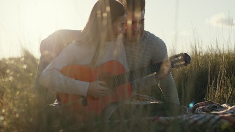Romantic couple hugs each other sitting in the countryside and plays the guitar