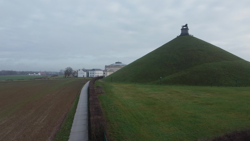 Butte Du Lion, lion’s mound, a hill at the Waterloo battlefield where Napoleon was defeated. Drone aerial upward shot on a cloudy winter day in farm fields