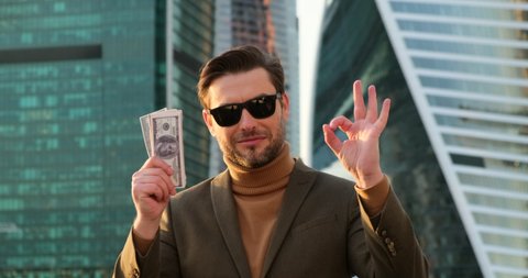 stylish man in a suit and turtleneck counting dollar bills near the office center on wall street new york. the broker made his first trade and made a profit. millionaire exchanged bitcoin for dollars