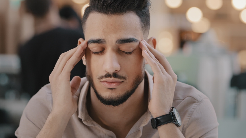 Close-up young unhealthy sad guy massaging temples suffering from headache unhappy depressed arab man have strong painful feeling migraine stressful condition difficult period of life chronic fatigue | Shutterstock HD Video #1085021311