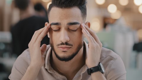Close-up young unhealthy sad guy massaging temples suffering from headache unhappy depressed arab man have strong painful feeling migraine stressful condition difficult period of life chronic fatigue